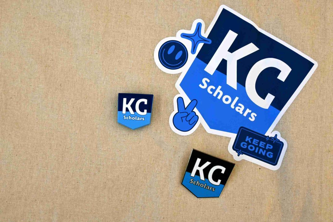 Three KC Scholars stickers and two blue graphic stickers are arranged on a beige fabric background, celebrating how KC Scholars Ambassadors are making an impact.