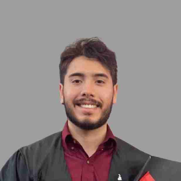 A young man wearing a maroon shirt and black graduation gown smiles at the camera against a plain gray background, ready to launch your future.