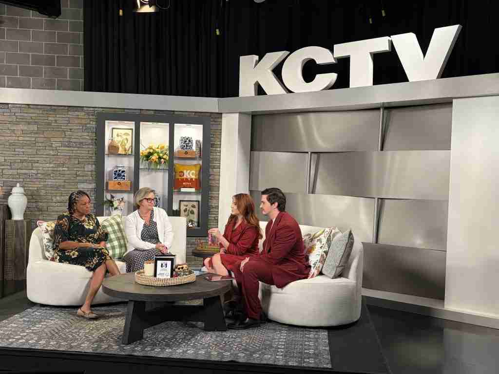 Four people sit on couches in a TV studio set with a “KCTV” sign above them, engaged in conversation about back to school topics such as college scholarships and skills training. Shelves and decor are visible in the background.
